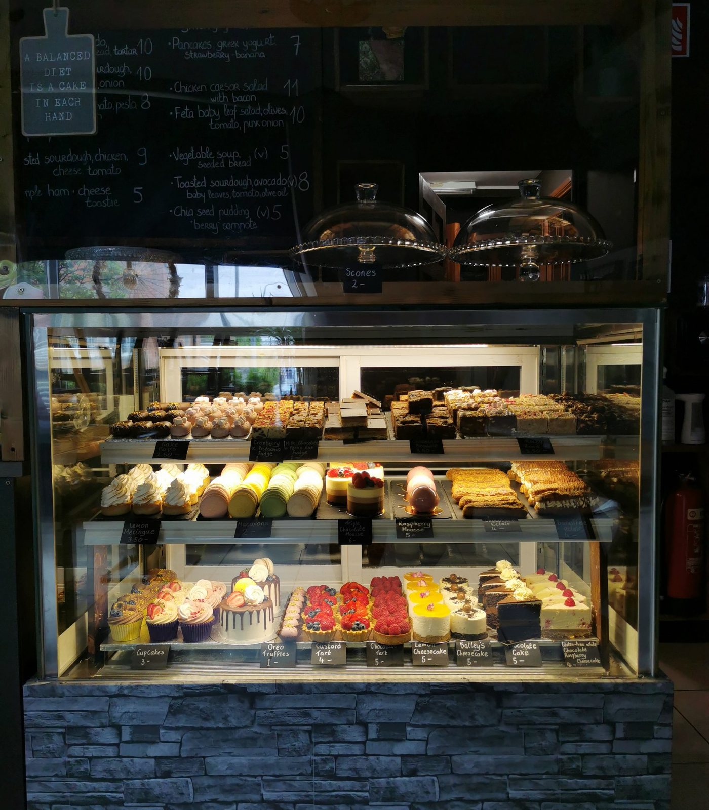 The pastry counter at Café Nua Belturbet — homemade cakes, tarts, macarons and a chalkboard lunch menu