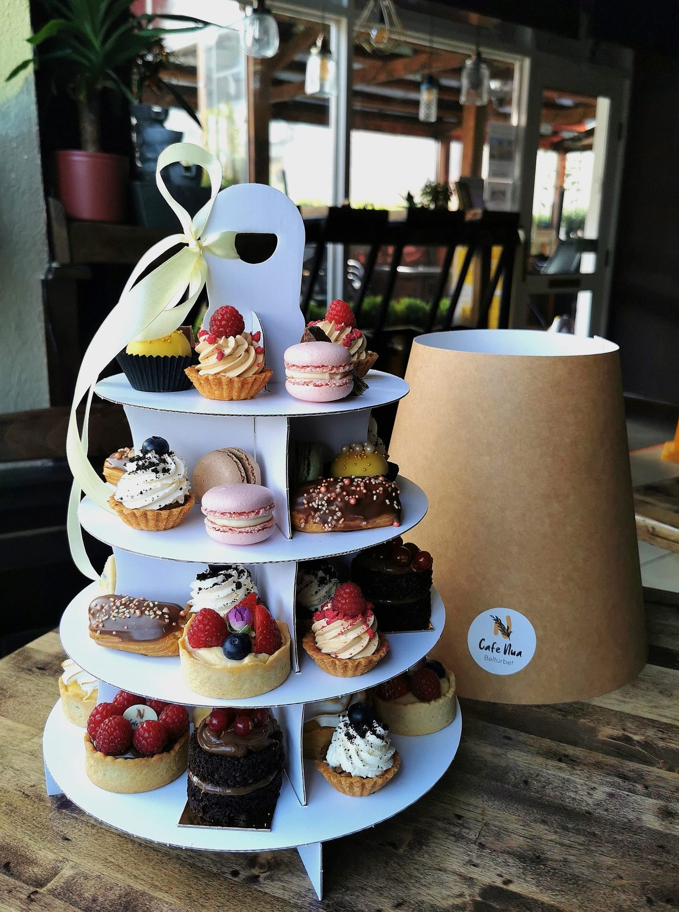 A four-tier stand of homemade tarts, macarons and cakes at Café Nua, Belturbet, with the outdoor terrace behind